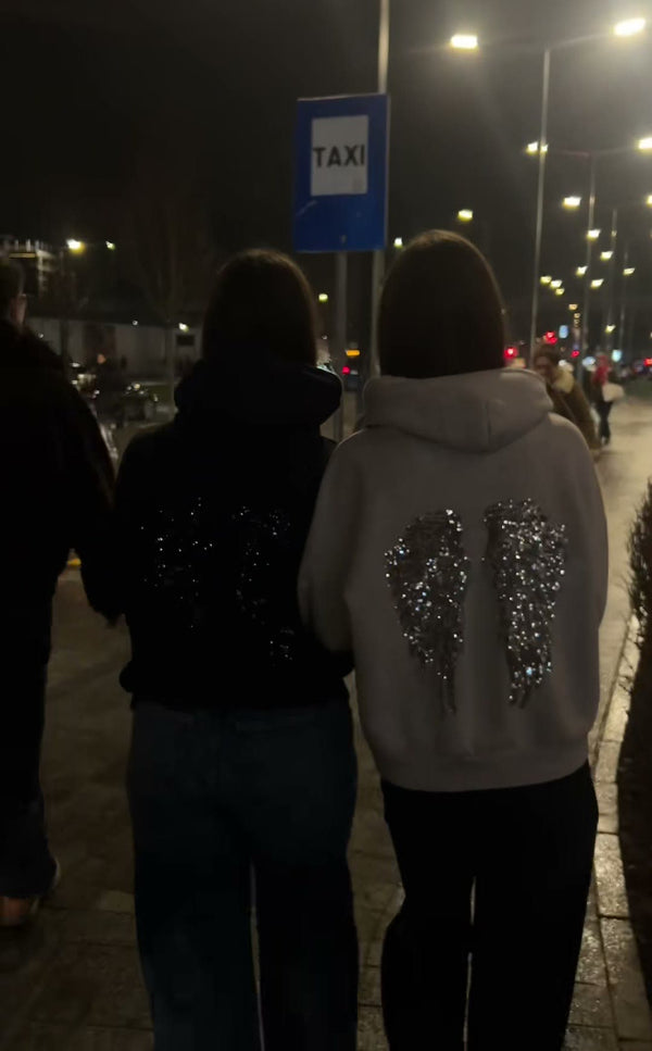 Heist Studio customers wearing the Angel Sequin Hoodie at night