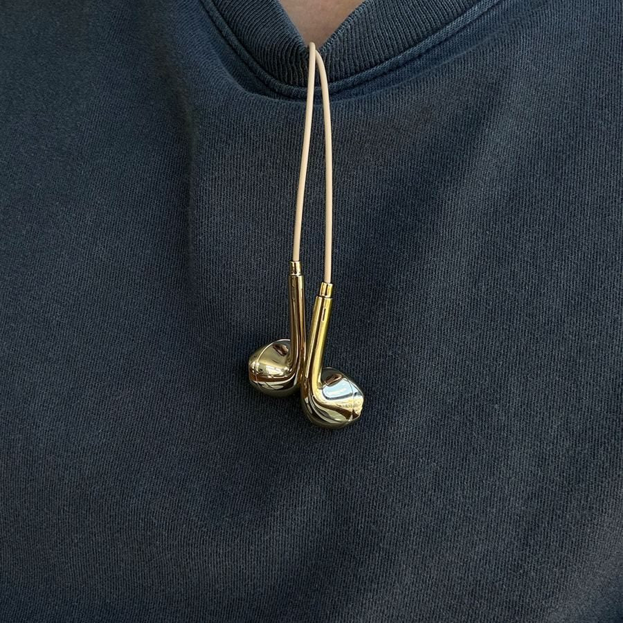 Gold earbuds hanging from a navy sweatshirt collar