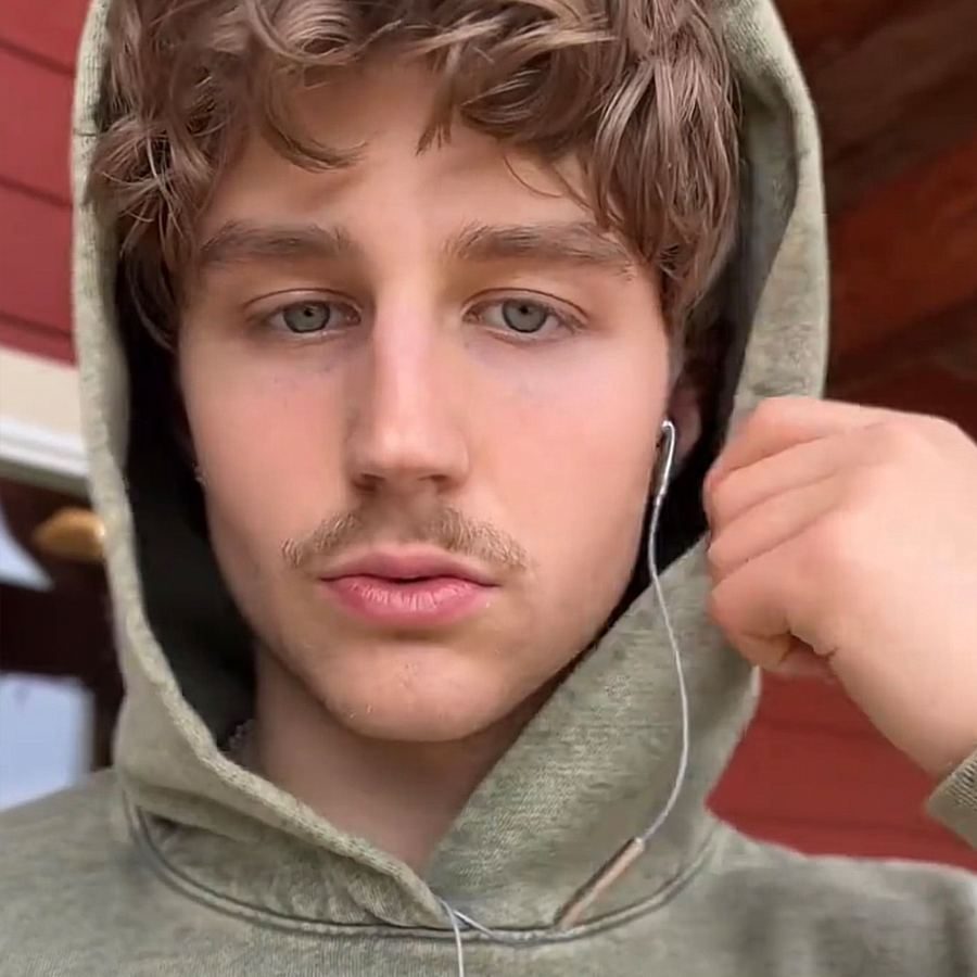 A young man in a hooded top with a wired earbud in his ear