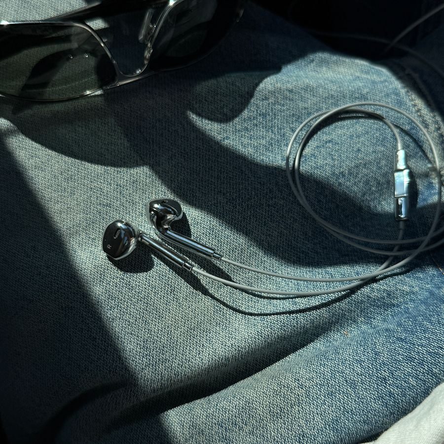 Silver earbuds and sunglasses on a denim jacket