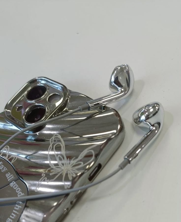 Silver earbuds beside a chrome phone case